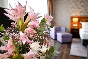Blumenstrauss, Detail mit Sitzsesel und Bett im Hintergrund