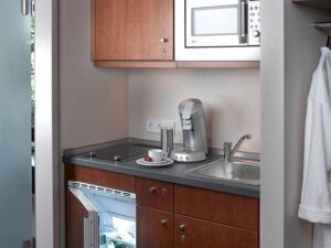 Küche mit Mikrowelle, Kühlschrank, Kaffeemaschine und Spüle